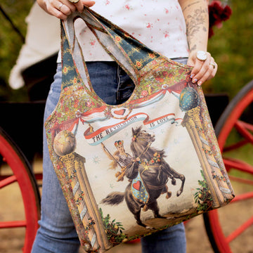 Person holding a tote bag with a horse and rider design, standing next to a red wagon.
