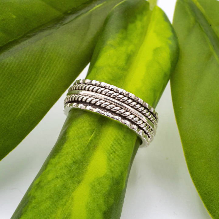 Silver ring with wavy design on a green leaf