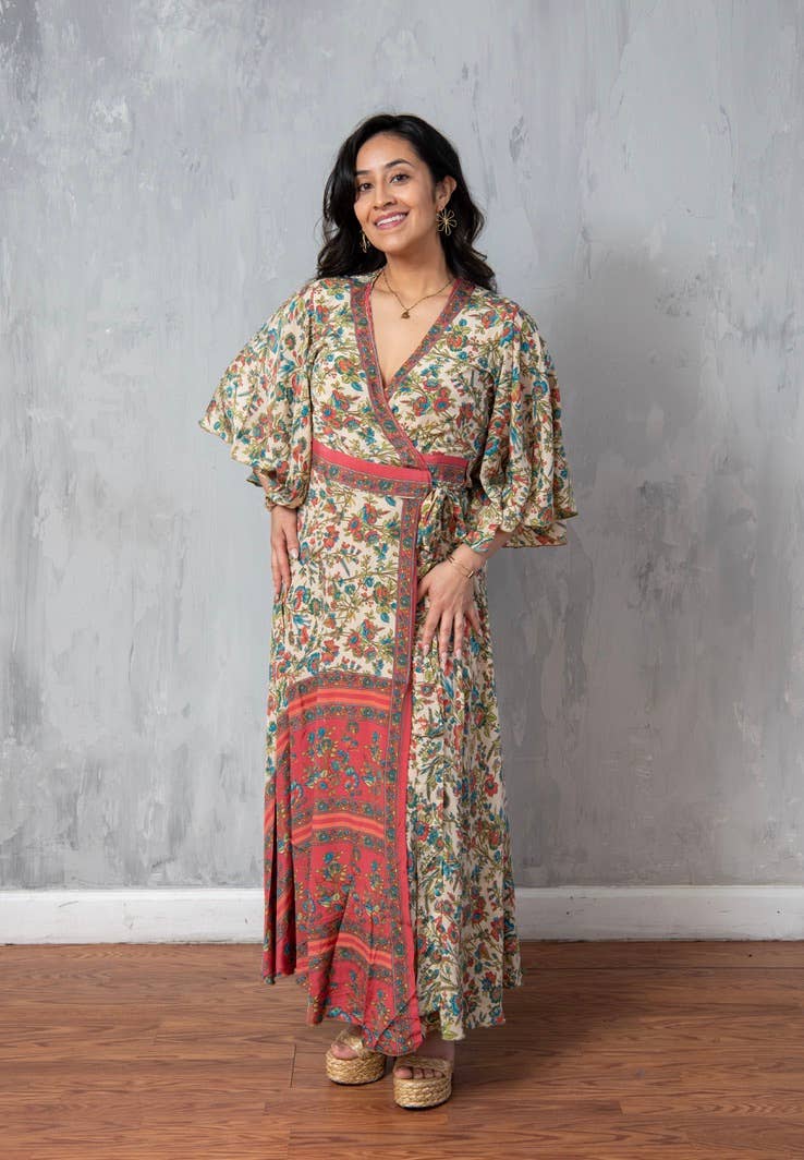 Woman wearing a floral dress standing against a gray wall.