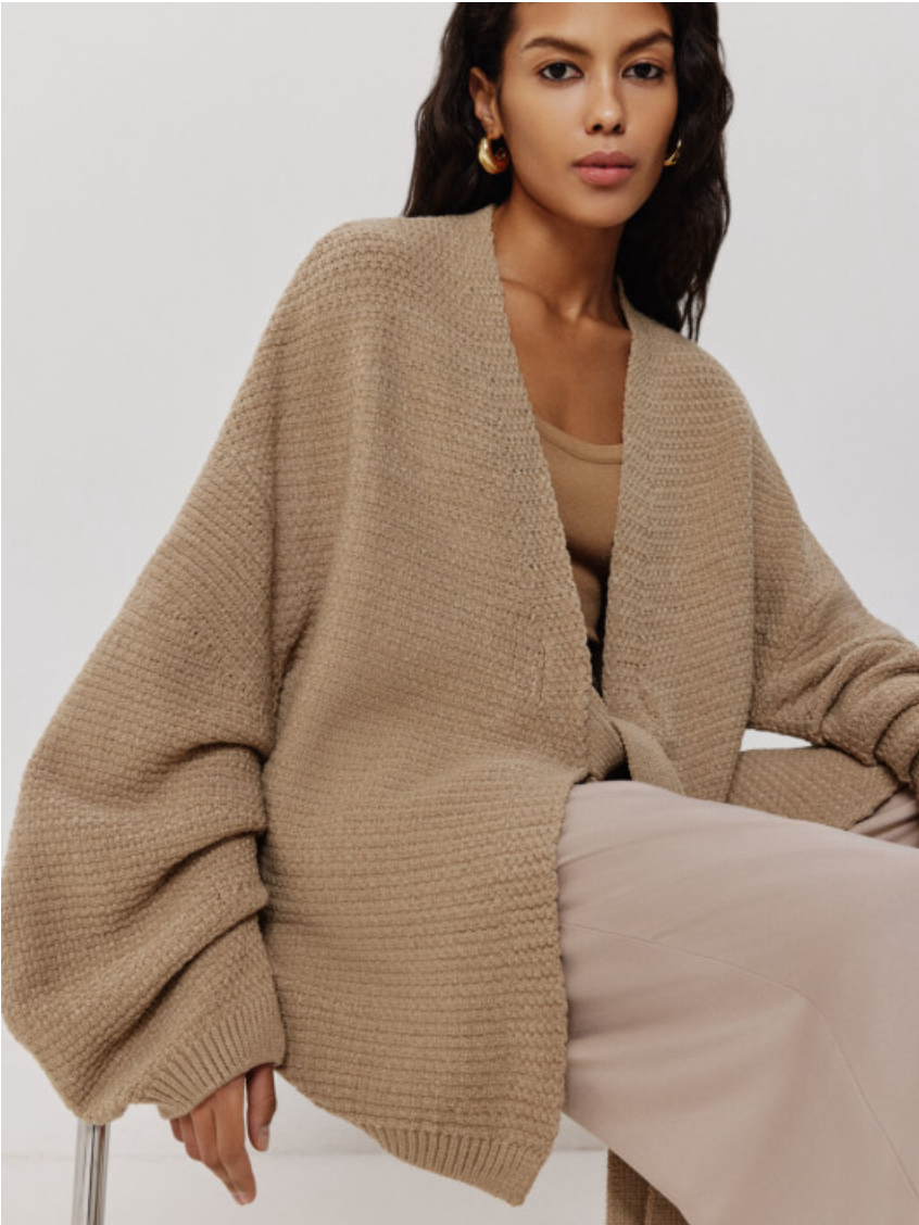 Woman wearing a beige cardigan and pants on a white background