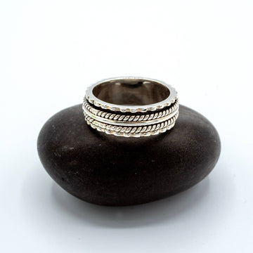 Stack of silver rings on a dark stone surface with a white background