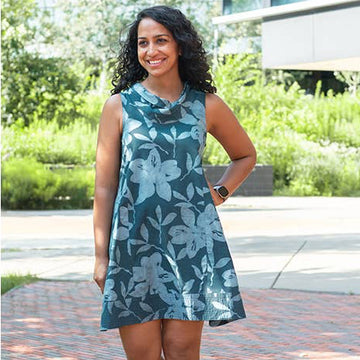 Woman wearing a blue floral dress standing outdoors on a sunny day.