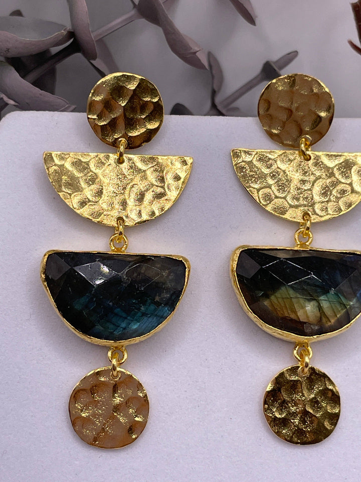 Gold and black earrings on a white surface