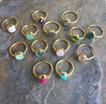 Gold rings with colorful gemstones on a stone surface
