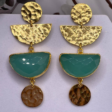 Gold and teal earrings on a white surface
