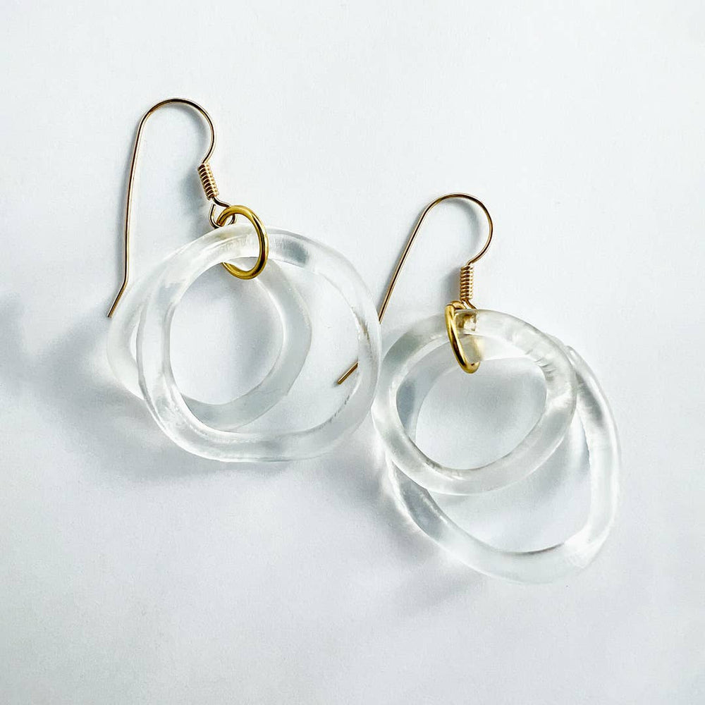 Clear circular earrings with gold hooks on a light gray background
