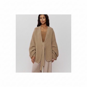 Woman wearing a beige cardigan over a beige top and pants on a white background