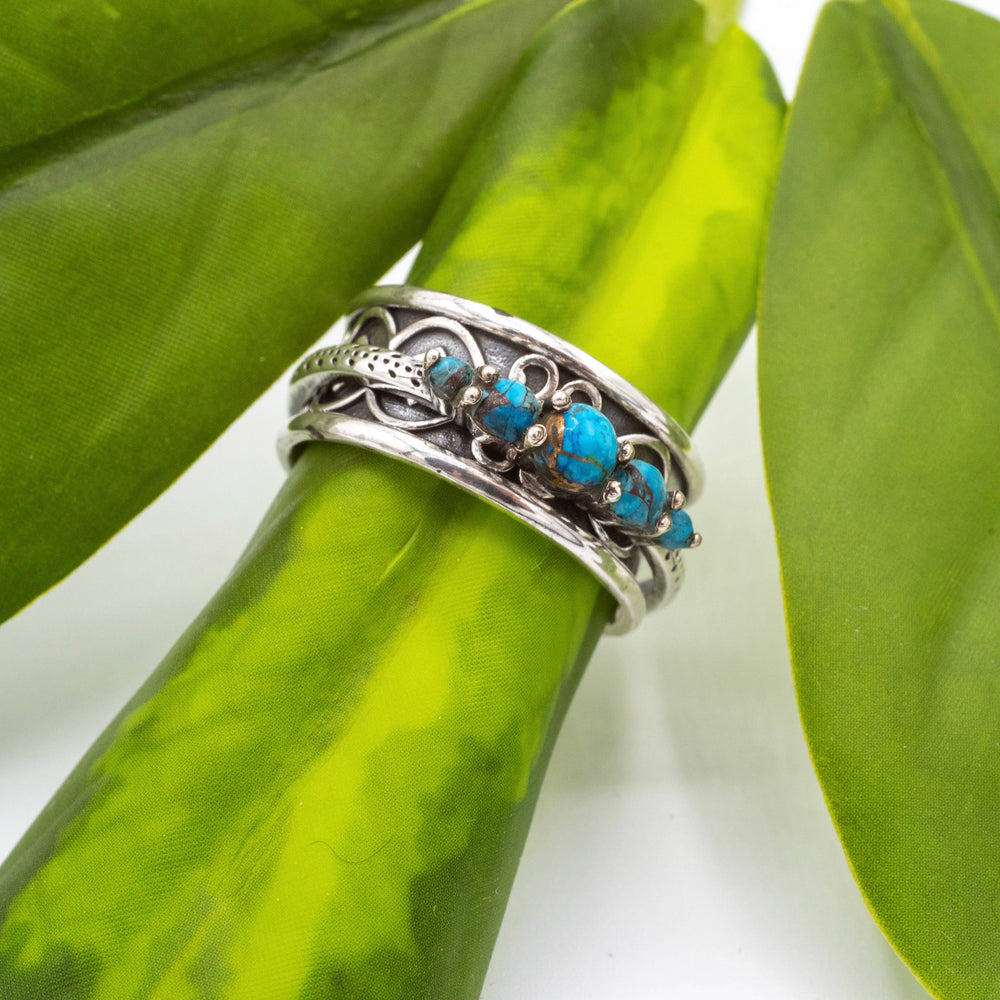Silver ring with turquoise stones on a green leaf