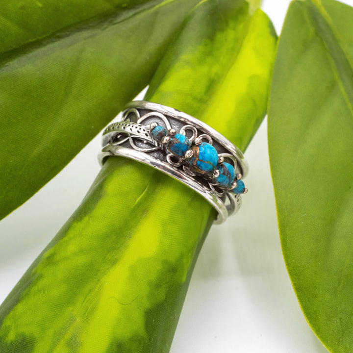 Silver ring with turquoise stones on a green leaf