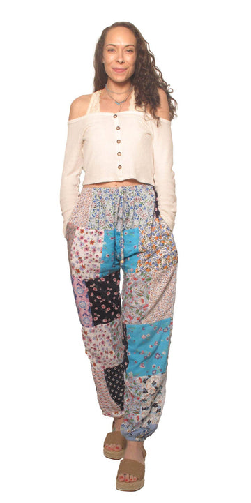 Woman wearing a white top and colorful patchwork pants on a white background