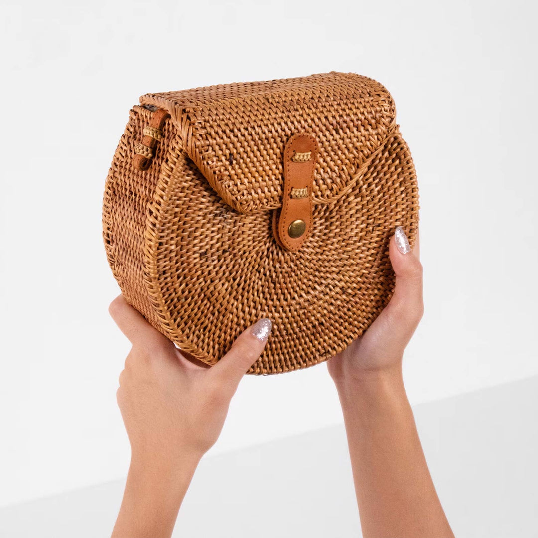 Brown woven handbag held by a person on a white background