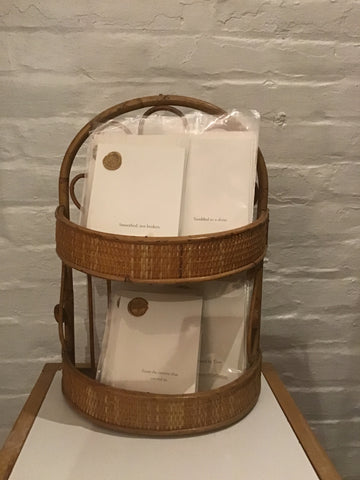 Wicker basket with transparent lid containing folded white paper on a textured wall background