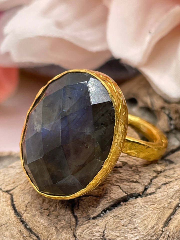 Gold ring with a large black gemstone on a wooden surface
