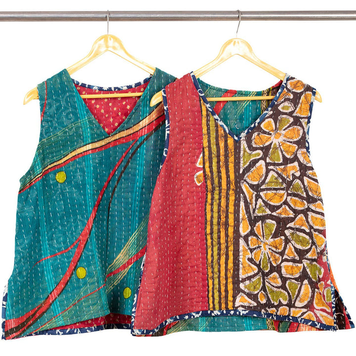 Two colorful patterned tops on hangers against a white background