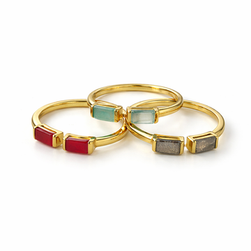 Three gold rings with colored gemstones on a white background
