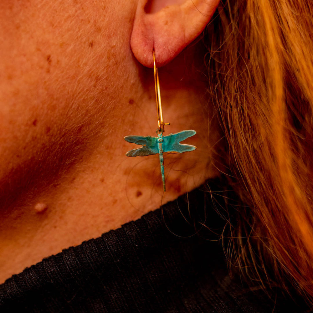 Model wearing Small brass patina dragonfly dangle earrings