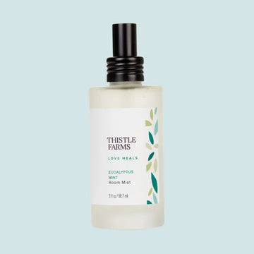Bottle of Thistle Farms Eucalyptus Mint Room Mist on a light blue background