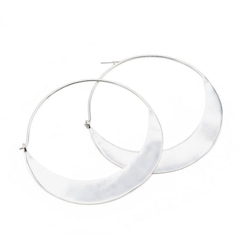 Close-up of a woman wearing a large hoop earring against a neutral background