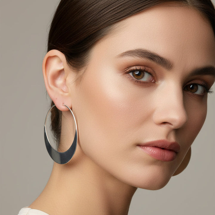 Close-up of a woman wearing a large hoop earring against a neutral background
