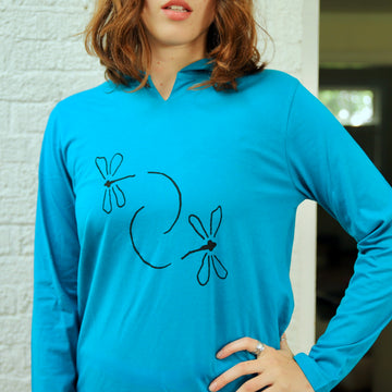 A woman wearing a teal hoodie with two dragonfly designs on the front.