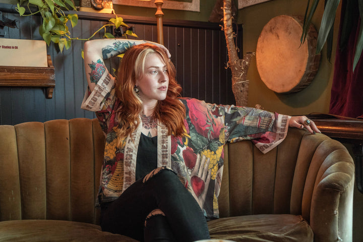 Person sitting on a couch with a colorful jacket, surrounded by decorative items in a room.