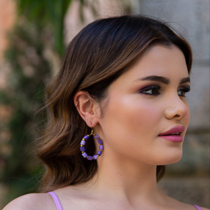 Woman wearing a purple top with a blurred outdoor background