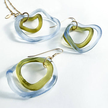 Set of heart-shaped earrings with green and clear design on a white background
