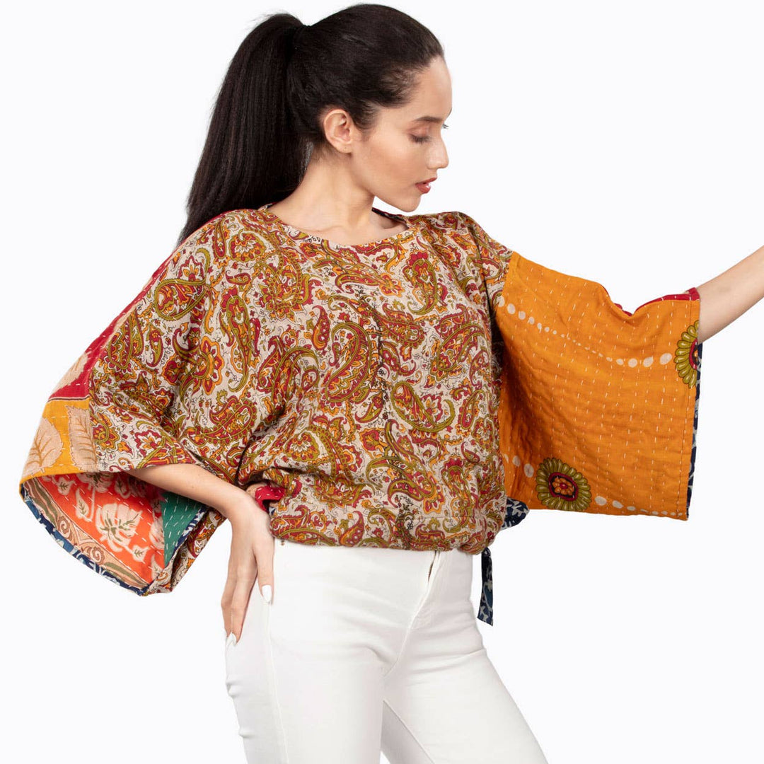 Woman wearing a colorful patterned top with bell sleeves on a white background
