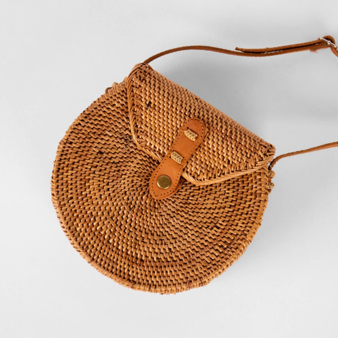 Brown woven handbag with a leather strap on a light gray background