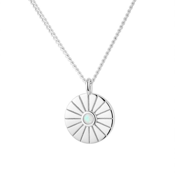 Silver necklace with a round pendant featuring a central gemstone on a white background