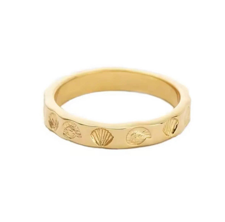 Gold ring with shell designs on a white background