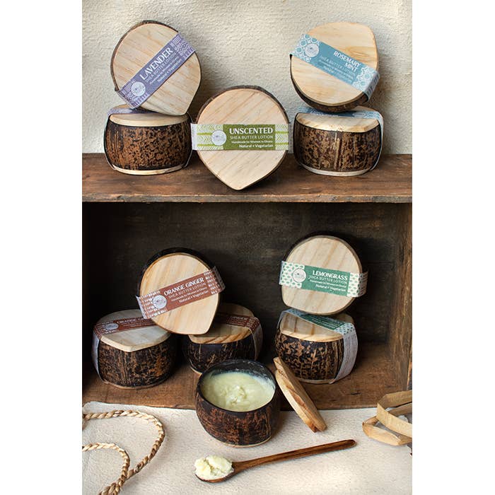 Coconut shells with candle wax inside, labeled with different scents, on a wooden shelf.