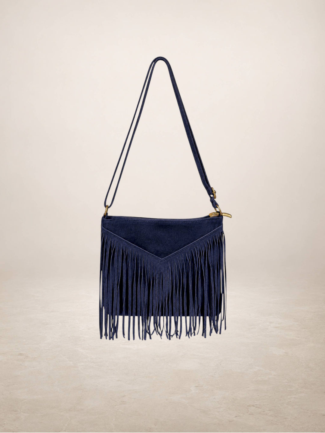 A navy blue suede fringe shoulder bag with a matching shoulder strap and gold-tone hardware, shown against a neutral beige background.