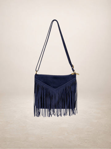 A navy blue suede fringe shoulder bag with a matching shoulder strap and gold-tone hardware, shown against a neutral beige background.