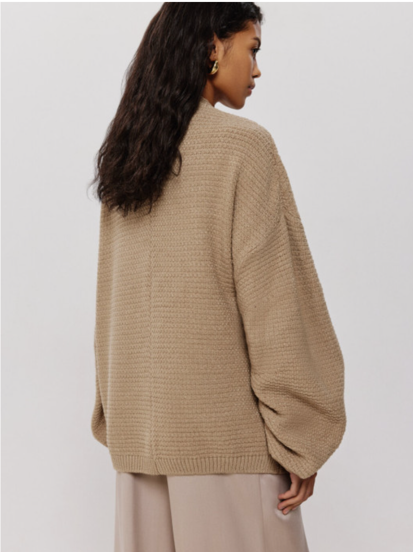 Person wearing a beige sweater on a plain background