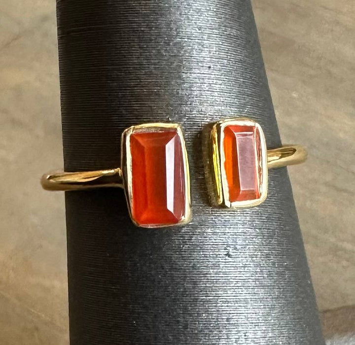 Pair of gold rings with red stone on a textured surface