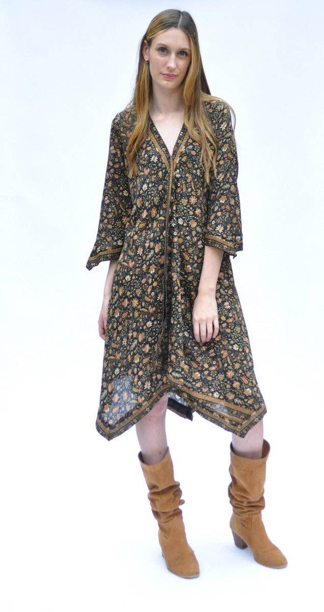 A woman modeling a long-sleeved, knee-length floral print dress with a V-neck and three-quarter sleeves, paired with brown slouchy knee-high boots, against a plain white studio background.