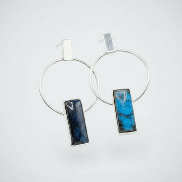 Pair of hoop earrings with blue stone pendants on a white background