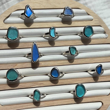 Set of blue and green ring designs on a wooden display block.