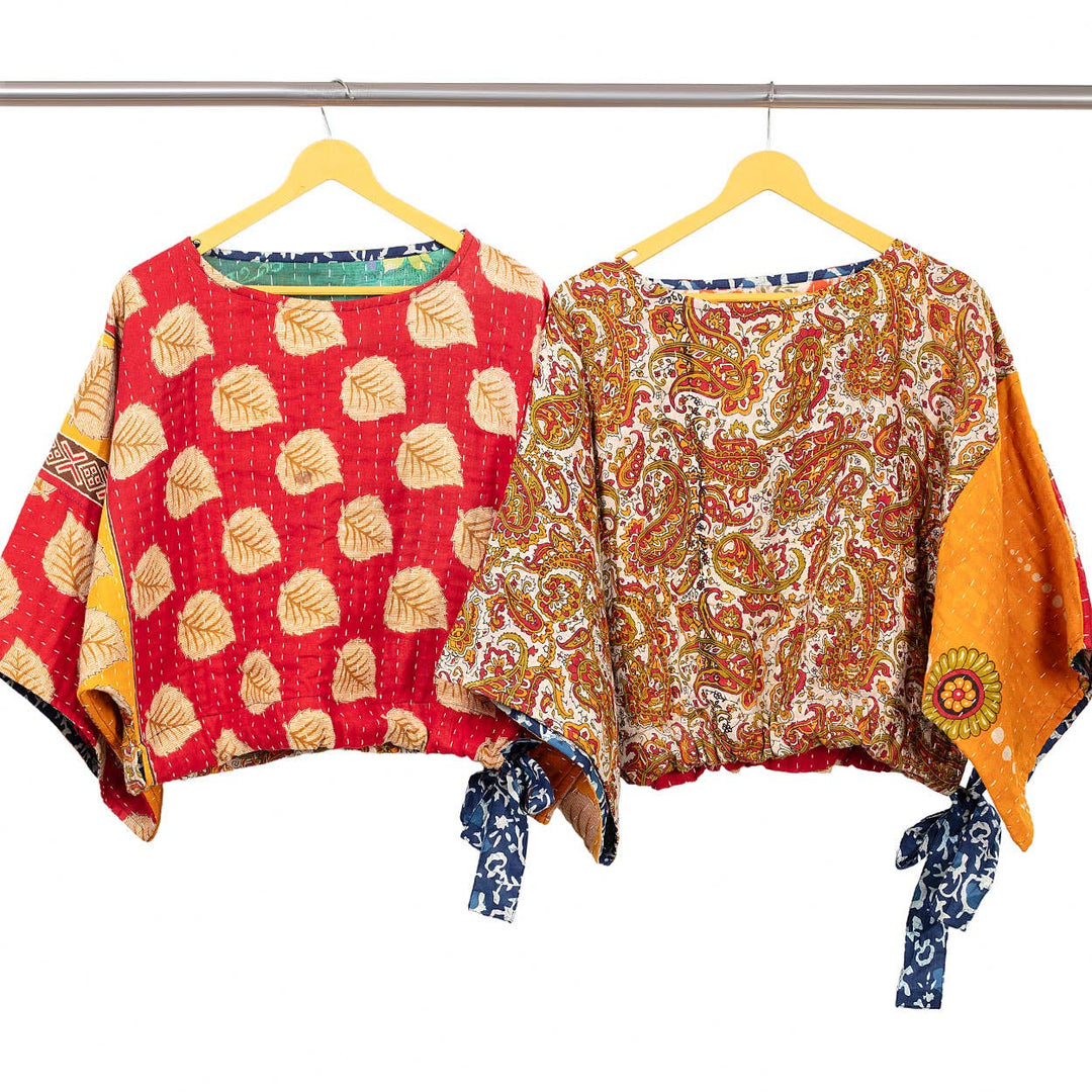 Two colorful patterned tops on hangers against a white background