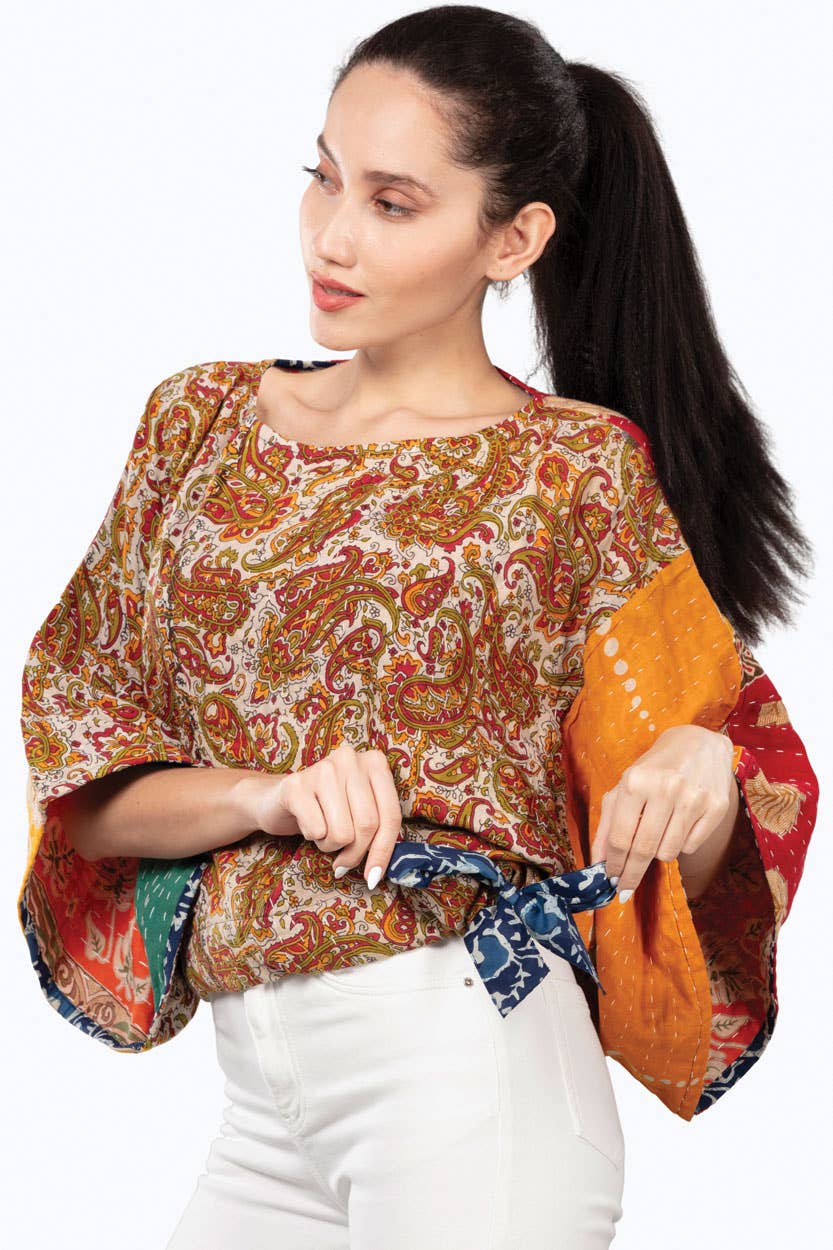 Woman wearing a colorful patterned top with a plain background