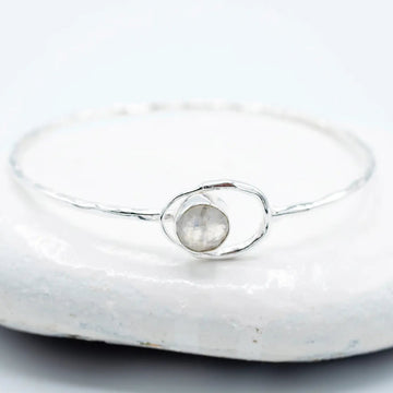 Silver ring with a central gemstone on a light background