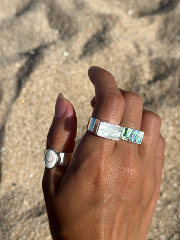 Hand wearing two rings on a sandy background