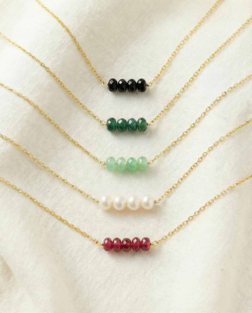 Set of gold necklaces with various colored beads on a white background