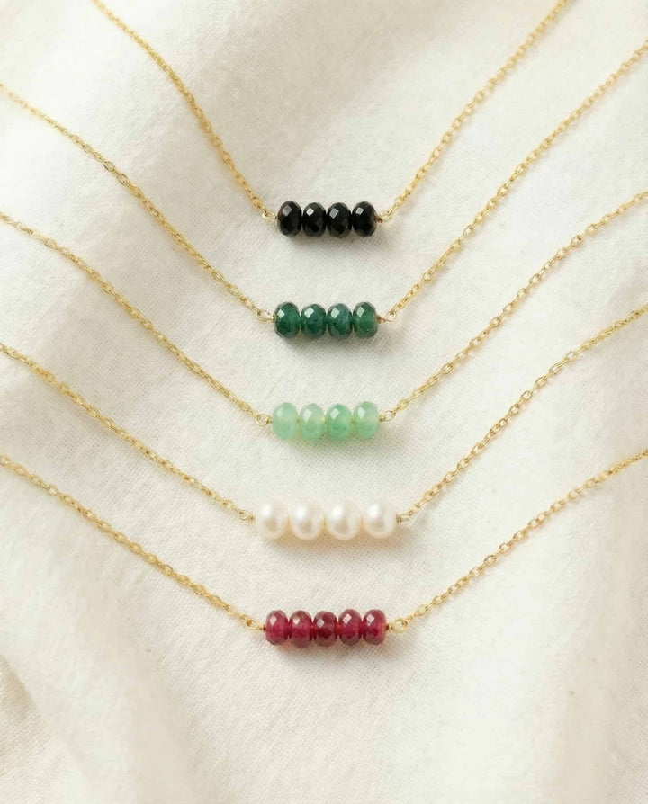 Set of gold necklaces with various colored beads on a white background