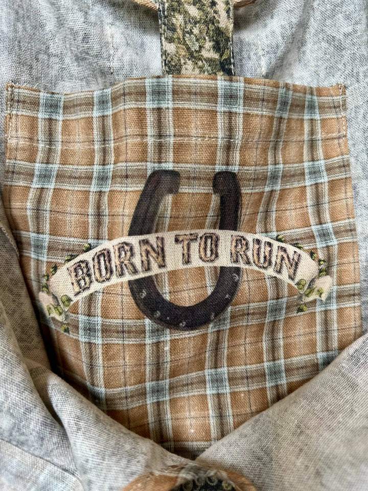 Plaid bag with horseshoe and 'Born to Run' text on a textured surface