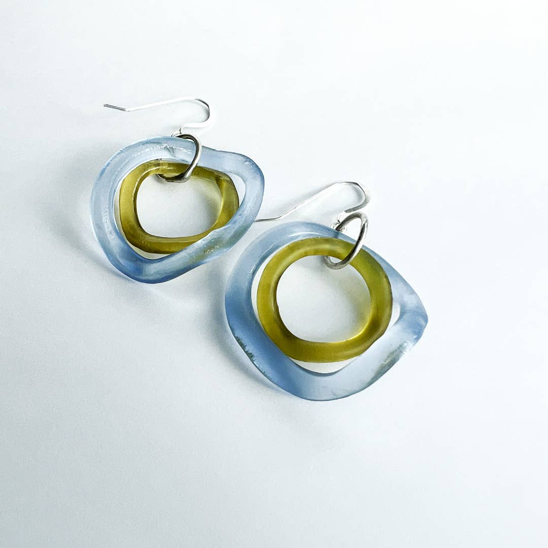 Pair of earrings with blue and green circular design on a light gray background