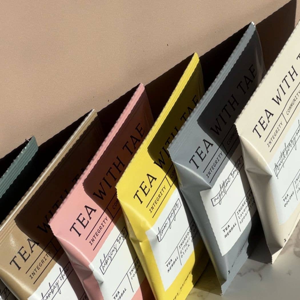 Assorted tea packages with visible branding on a neutral background
