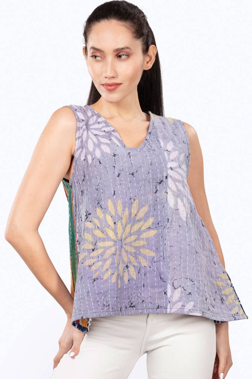 Woman wearing a sleeveless purple top with floral patterns on a white background